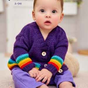 May include: A purple knitted cardigan with rainbow stripes on the sleeves. The cardigan has a button closure and is worn by a baby.