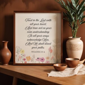 May include: A framed print with the text "Trust in the Lord with all your heart... Proverbs 3:5-6". The print has a floral border and is displayed on a wooden surface. Decorative vases and bowls are also present.