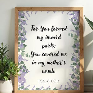 Puede incluir: Una impresión enmarcada con un marco de madera clara. La impresión presenta el texto "For You formed my inward parts; You covered me in my mother's womb. PSALM 139:13" en escritura negra. El texto está rodeado de acentos florales morados y verdes al estilo acuarela.