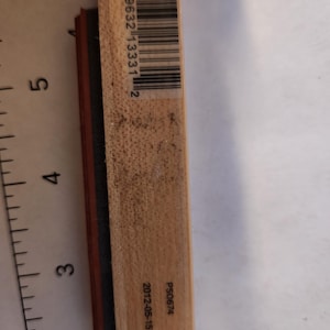 May include: A rectangular wooden stamp with a barcode and the numbers "7 29632 13331 2" printed on it. The stamp also has the text "PS0674" and the date "2012-05-15 1083870" printed on it. The stamp has a red and black rubber stamp.