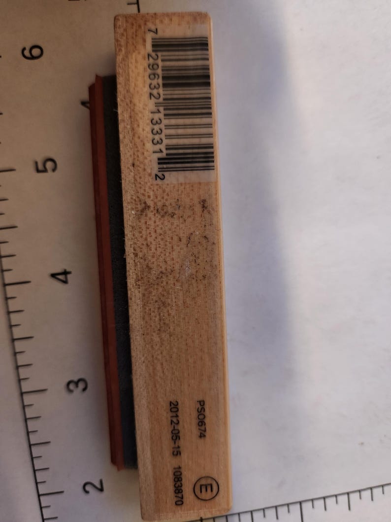 May include: A rectangular wooden stamp with a barcode and the numbers "7 29632 13331 2" printed on it. The stamp also has the text "PS0674" and the date "2012-05-15 1083870" printed on it. The stamp has a red and black rubber stamp.