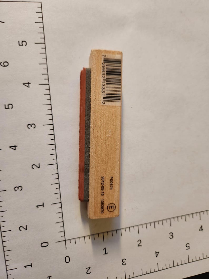 May include: A rectangular wooden stamp with a black and red rubber stamp pad. The stamp has a barcode and the text "P50674" and "2012-05-15 1083870" printed on it. The stamp is approximately 3 inches long.