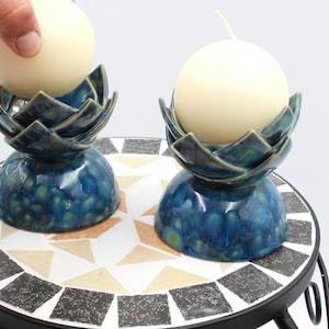 A pair of handmade ceramic candle holders in blue/greenish crystaline color for various candle sizes