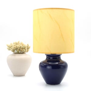 Blue ceramic bedside table lamp with parchment style yellowish fabric shade