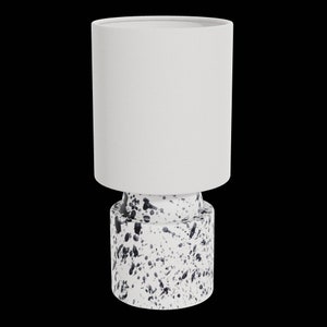 May include: A white ceramic table lamp with a white fabric shade. The base of the lamp has a black and white splatter paint design.