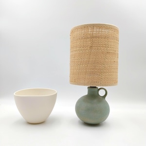 Greenish, rusty patina matte stoneware ceramic table lamp in bottle shape with handle raffia/rattan fabric shade or green felt shade