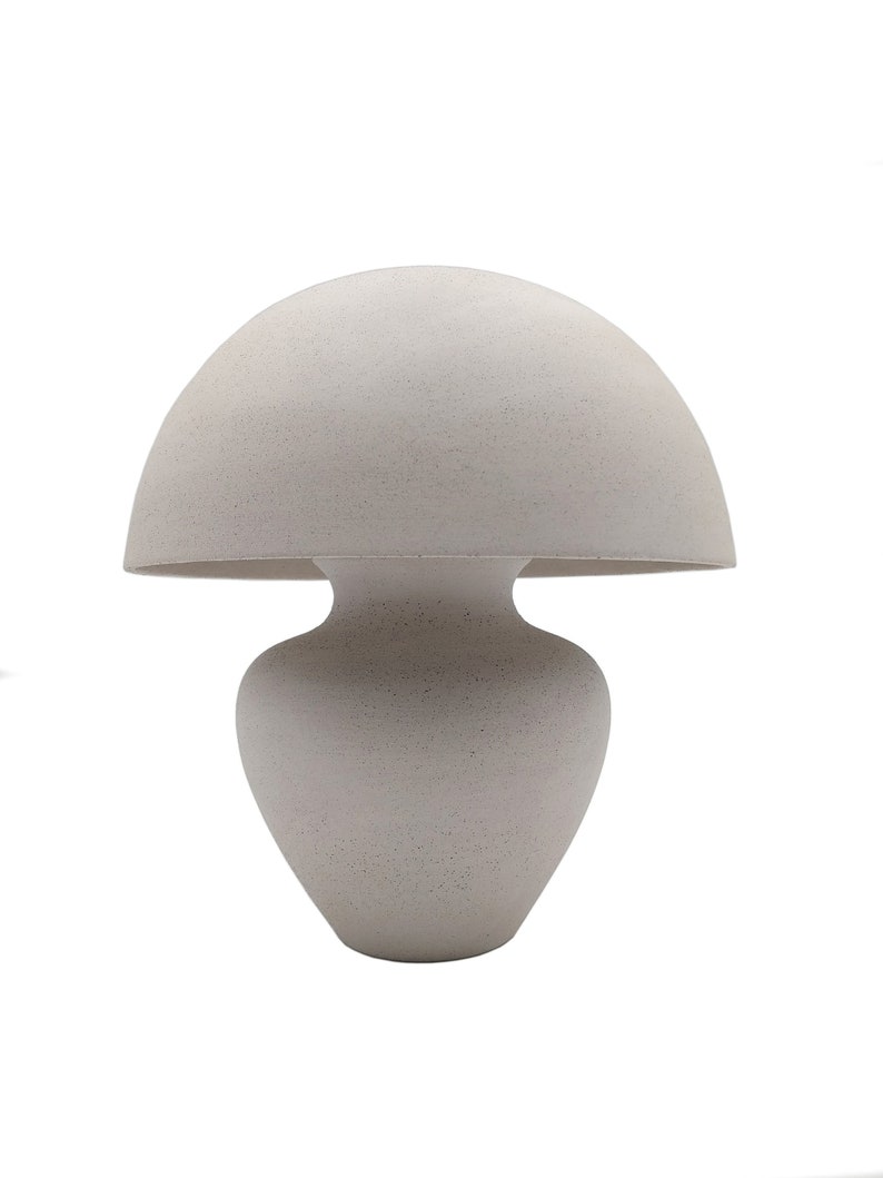 May include: A white ceramic table lamp shaped like a mushroom with a rounded top and a wide base.