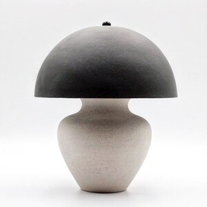 May include: A ceramic table lamp with a white base and a black dome-shaped shade.