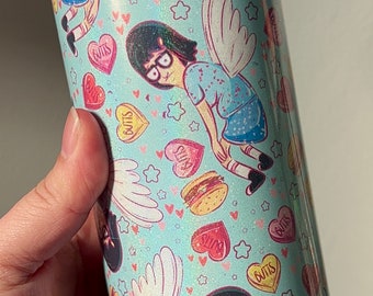 May include: A light blue tumbler with a white lid. The tumbler has a pattern of cartoon characters with wings, hearts, stars, and candy hearts that say "Butts" and "Slims".