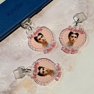 May include: Three pink heart-shaped acrylic charms with a photo of a man and the text "but daddy I love him".