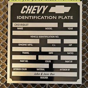 May include: Black and silver Chevy identification plate with spaces for vehicle details. The plate includes fields for make, model, year, and vehicle identification number. It also has spaces for engine, paint, and interior information. The text "John & Jane Doe" is visible.