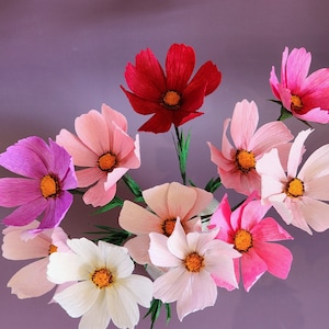 May include: A bouquet of paper flowers in various shades of pink, white, and red. The flowers are arranged in a cluster and have a delicate, layered appearance.