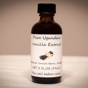 Op de afbeelding: Een glazen fles met pure vanille-extract uit Oeganda met een zwarte dop. Het etiket is wit met zwarte tekst die "Pure Ugandan Vanilla Extract" en "NET 2 FL.OZ (59ml)" luidt. Het etiket bevat ook een klein beeld van vanillebonen.