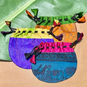 May include: Three colourful drawstring pouches made of silk fabric with intricate patterns. The pouches are in shades of green, yellow, orange, purple, pink, and blue. Each pouch has a black drawstring and tassel.
