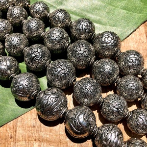 Peut inclure: Un collier en argent avec de gros perles rondes. Chaque perle est finement sculptée avec un motif floral.