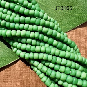 May include: Close-up of strands of light green beads. The beads are small, cylindrical, and have a matte finish. The text "JT3165" is visible in the upper right corner. The beads are likely for jewelry making.