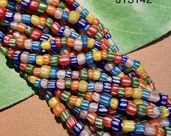 May include: A collection of multi-coloured glass beads arranged in several strands. Each bead features a striped pattern with white lines against vibrant colours including red, blue, green, yellow, and orange. The text JT3142 is visible.