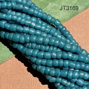 May include: A strand of opaque teal blue glass beads with a smooth, rounded shape. The beads are strung together in a dense, multi-row formation. The text JT3169 is printed in black in the upper right corner of the image area.