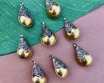 May include: Eight gold-colored teardrop-shaped pendants with intricate silver designs and blue and red gemstones.