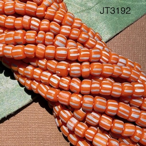 May include: A collection of small, round, orange beads arranged in multiple parallel strands. Each bead features distinct vertical white stripes running around its circumference. The text JT3192 is clearly visible in the upper right corner.