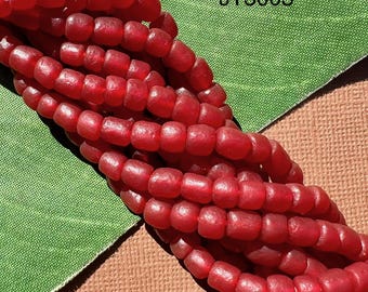 May include: A strand of deep red glass beads, each bead is slightly rounded and has a textured surface. The beads are arranged in a loose pile on a green and brown surface. The text "UT3003" is visible in the upper right corner of the image.