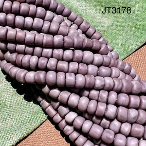 以下が含まれることがあります： マーブル模様の薄いパープルのガラスビーズのストランド。ビーズは丸く、わずかに不規則な形をしています。ビーズは透明な糸に糸でつながれています。