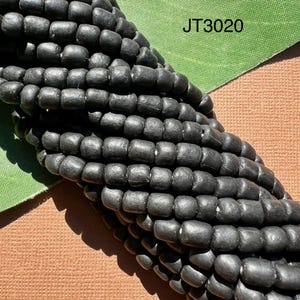 Könnte beinhalten: Nahaufnahme einer schwarzen Perlenkette. Die Perlen sind klein und rund und in einem engen, gleichmäßigen Muster angeordnet. Die Perlen bestehen aus einem glatten, matten Material. Das Bild ist mit "JT3020" beschriftet.