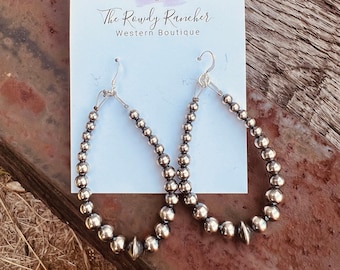 May include: A pair of silver hoop earrings with a beaded design. The earrings are displayed on a white card with the text "The Rowdy Rancher Western Boutique".