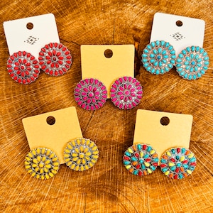 May include: Four pairs of round, silver stud earrings with colorful, multi-colored, turquoise, yellow, red, and pink stones. The earrings are displayed on white and brown card stock.