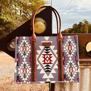May include: A gray and white tote bag with a geometric pattern and brown leather handles. The bag has the word "Wrangler" printed on the front.