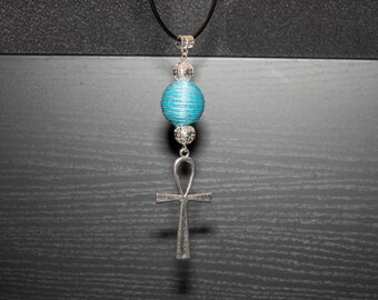 Peut inclure: Un collier avec un pendentif ankh en argent et une perle rayée bleue et argentée.