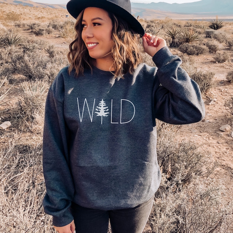 May include: A dark gray sweatshirt with the word "WILD" printed in white with a stylized pine tree graphic in the middle of the word.