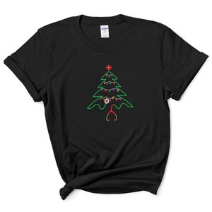 以下が含まれることがあります： 緑色のクリスマスツリーのデザインが施された黒いTシャツ。ツリーはカラフルなライトと赤いオーナメントで飾られています。ステートスコープがツリーの根元にあります。