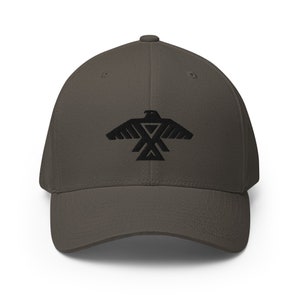 May include: A dark gray baseball cap with a black embroidered eagle design. The eagle is stylized with a geometric pattern.
