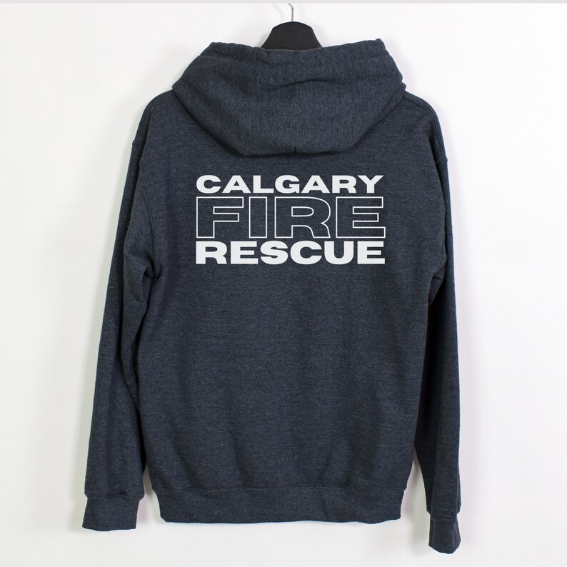 Peut inclure: Un sweat &agrave; capuche gris fonc&eacute; avec une fermeture &eacute;clair blanche. Le dos du sweat-shirt porte l'inscription "CALGARY FIRE RESCUE" en blanc.