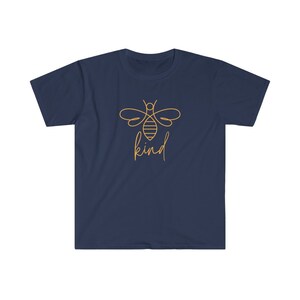Puede incluir: Camiseta azul marino con un contorno dorado de una abeja y la palabra "kind" en escritura manuscrita. El dise&ntilde;o est&aacute; centrado en la parte delantera. La camiseta tiene mangas cortas y cuello redondo.