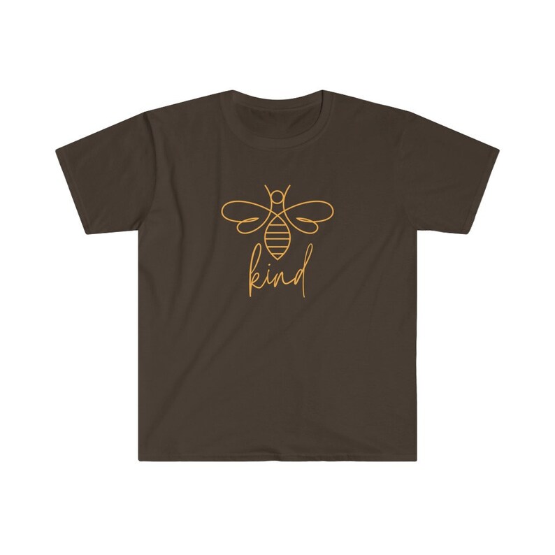 Puede incluir: Camiseta marr&oacute;n con un dise&ntilde;o minimalista de una abeja dorada y la palabra "kind" escrita a mano. El dise&ntilde;o dorado de la abeja y el texto contrastan con el fondo marr&oacute;n de la camiseta.