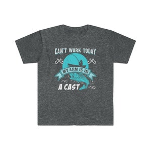 May include: Dark heather grey t-shirt with a fishing themed graphic. The graphic features a blue fish, a fishing rod, and the text "Can't work today, my arm is in a cast".