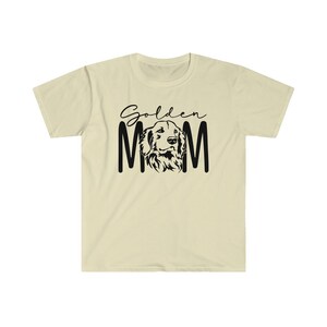 K&ouml;nnte beinhalten: Ein hellbeiges T-Shirt mit schwarzem Text, der "Golden Mom" lautet, und einer schwarzen Silhouette eines Golden Retriever-HundeKopfes.