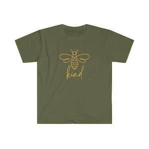 Puede incluir: Camiseta verde oliva con un dise&ntilde;o de abeja dorada y la palabra "kind" en cursiva. La camiseta tiene cuello redondo y mangas cortas. El dise&ntilde;o est&aacute; centrado en la parte delantera.
