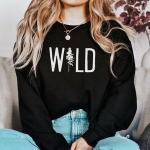 May include: Black sweatshirt with the word "WILD" printed in white with a small pine tree graphic in the middle of the word.