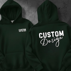 Puede incluir: Sudadera con capucha verde oscuro con bolsillo delantero y capucha. La parte delantera de la sudadera tiene el texto "CUSTOM TEXT OR LOGO" en blanco. La parte trasera de la sudadera tiene el texto "CUSTOM Design" en blanco.