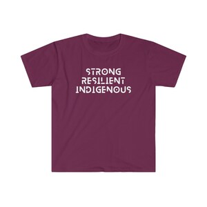 May include: A maroon t-shirt with the words "STRONG RESILIENT INDIGENOUS" printed in white on the front.