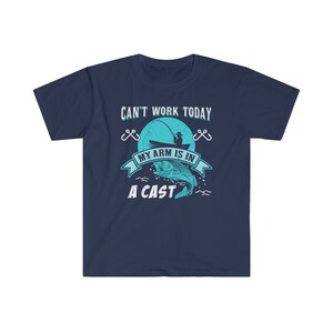 May include: Navy blue t-shirt with a graphic of a fisherman in a boat with a fish jumping out of the water. The text on the shirt reads "Can't work today, my arm is in a cast."