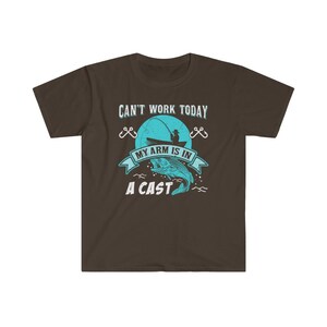May include: A brown t-shirt with a blue graphic of a fisherman in a boat with a fish on a hook. The text on the shirt reads "Can't work today, my arm is in a cast."
