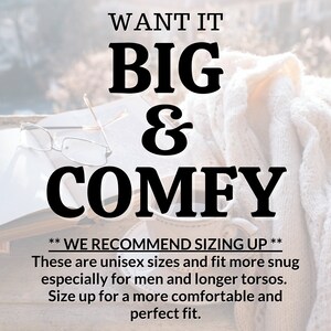 May include: Text overlay on a blurred background image of a book, glasses, and a mug. The text reads "WANT IT BIG & COMFY" and "WE RECOMMEND SIZING UP" followed by "These are unisex sizes and fit more snug especially for men and longer torsos. Size up for a more comfortable and perfect fit."