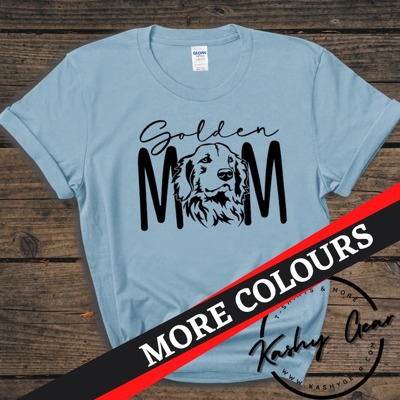 K&ouml;nnte beinhalten: Ein hellblaues T-Shirt mit einer schwarzen Silhouette eines Golden Retrievers und dem Text "Golden Mom". Der Text "More Colours" ist in Rot und Schwarz auf wei&szlig;em Hintergrund.
