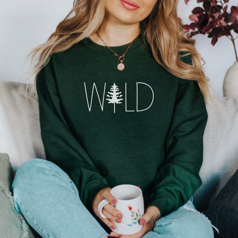 May include: A dark green sweatshirt with the word "WILD" printed in white with a small pine tree graphic in the middle of the word.
