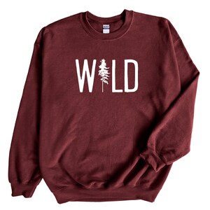 May include: Burgundy sweatshirt with white text that reads "WILD" with a stylized pine tree in the middle of the word.