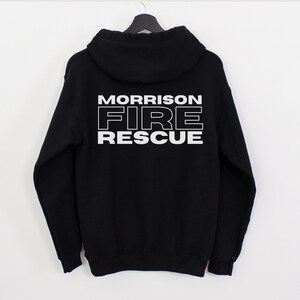 Peut inclure: Sweat-shirt &agrave; capuche noir avec un texte blanc au dos qui dit "MORRISON FIRE RESCUE".
